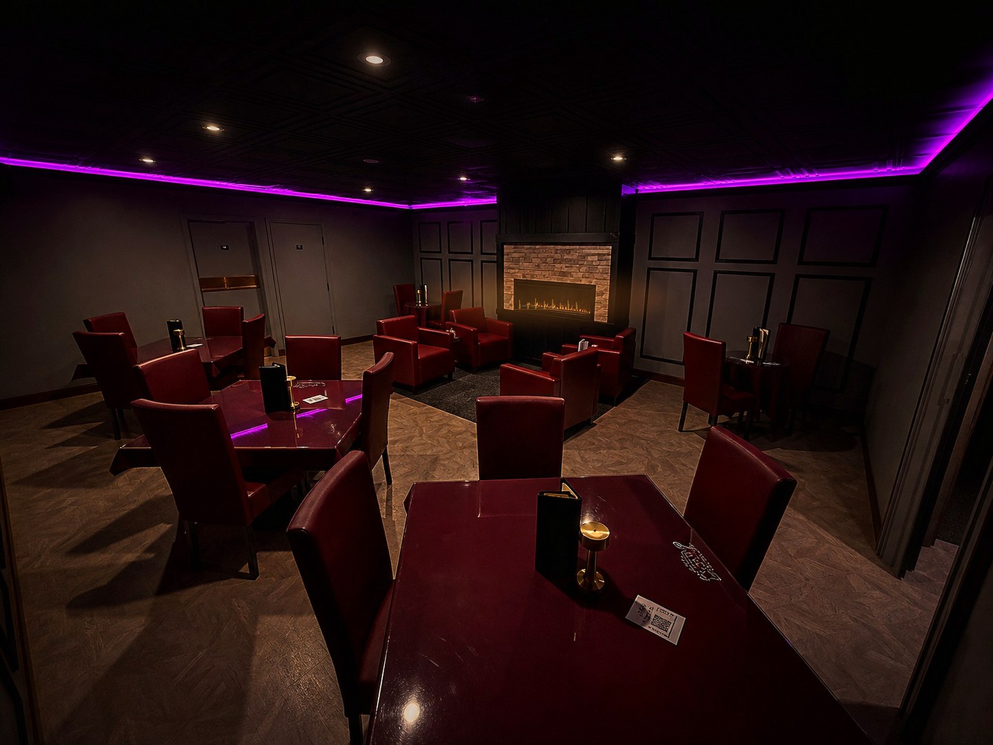 Private CK Downtown fireplace room with red seating, magenta LED ceiling light, and a warm fireplace